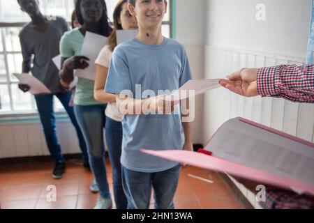 Groupe d'élèves multiethniques du secondaire qui se font des devoirs en classe Banque D'Images