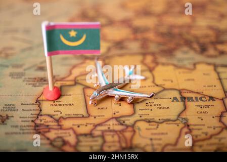 Le drapeau de la Mauritanie et l'avion sur la carte du monde. Le concept de voyage et de tourisme. Banque D'Images