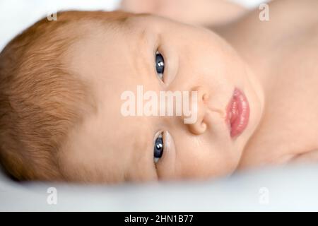 Gros plan du nouveau-né sur une couverture blanche. Mise au point douce. Un bébé de deux semaines dort bien sur le côté de son lit. enfant de 14 jours. Banque D'Images