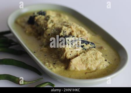 Curry de poisson Pomfret à base de noix de coco de style Kerala. Curry de poisson de couleur jaune sur fond blanc Banque D'Images