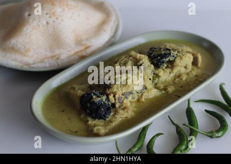 Curry de poisson Pomfret à base de noix de coco de style Kerala servi avec des trémies de riz. Communément appelé Appam et curry de poisson au Kerala. Cari jaune de poisson Banque D'Images