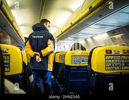 Un agent de bord Ryanair mâle contrôle les passagers à l'intérieur d'un Boeing 737 peu avant le décollage. C'est le vol FR121 de Londres Gatwick à Dublin. Banque D'Images