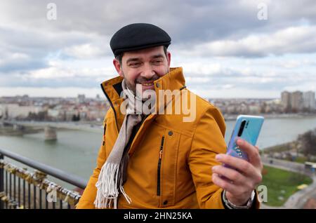 Portrait d'un homme souriant tenant son téléphone et prenant un selfie Banque D'Images