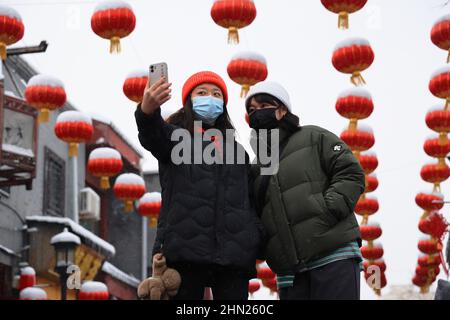 Pékin, Chine. 13th févr. 2022. Les gens prennent des selfies à la rue Qianmen à Beijing, capitale de la Chine, le 13 février 2022. Une chute de neige a frappé Beijing dimanche. Credit: Xing Guangli/Xinhua/Alay Live News Banque D'Images