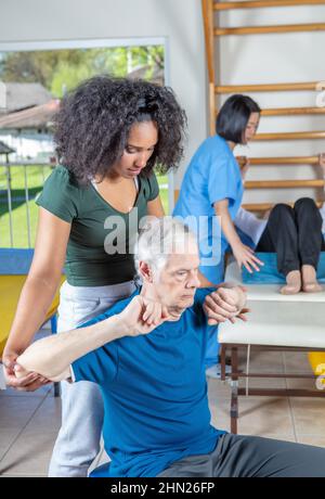 Couple heureux de personnes âgées souriant de formation à la salle de gym aidé par des entraîneurs asiatiques et africains. Les personnes âgées à la retraite vivent au meilleur de leur vie Banque D'Images