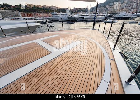 Le pont avant d'un énorme yacht dans le port de Monaco au coucher du soleil, le lieu d'atterrissage de l'hélicoptère, beaucoup de bateaux à moteur sont sur fond, le chrome Banque D'Images