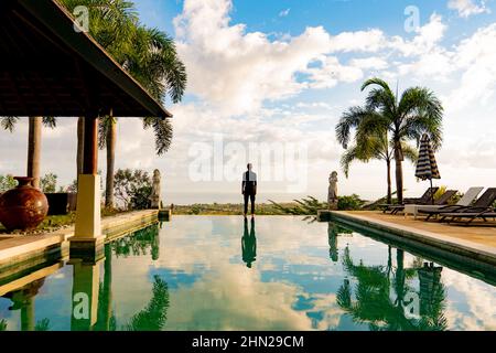 Un homme debout au bord de la piscine à débordement Banque D'Images