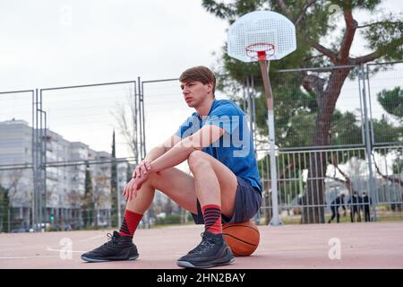 joueur de basket-ball assis sur le terrain Banque D'Images