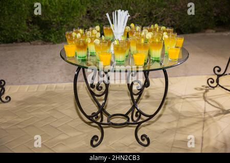 Cocktails alcoolisés de différentes couleurs avec des tranches d'orange lors d'une soirée en plein air dans un hôtel égyptien. Table en verre décorée sur un événement en plein air Banque D'Images