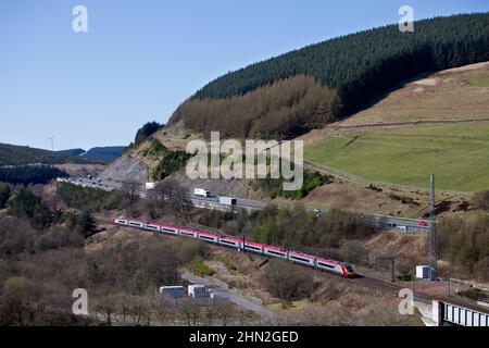 Virgin trains Alstom Pendolino train inclinable 390005 dans la campagne écossaise sur la ligne principale électrifiée de la côte ouest, par l'autoroute A74(M) Banque D'Images