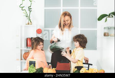 Maman fille et fils préparent un smoothie dans la cuisine. Amusez-vous et jouez avec les légumes. Une alimentation saine et un mode de vie sain pour les enfants. Nutrition végétalienne et a Banque D'Images