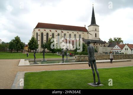 Piscine d'eau avec des sculptures modernes en plein air, église gothique et baroque de l'Exaltation de la Sainte Croix en arrière-plan, Litomysl, Tchéquie Banque D'Images