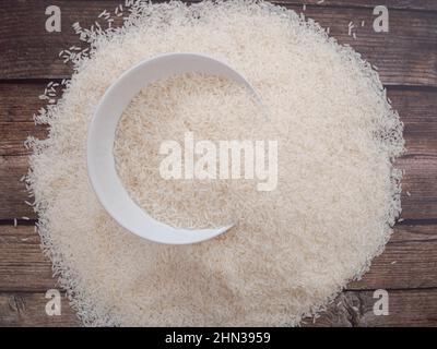 Gros plan sur le dessus du riz dans un bol blanc et éparpillé près de la table en bois avec un espace de copie pour le texte et le design Banque D'Images