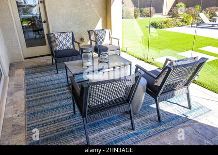 Patio arrière avec quatre fauteuils et table basse sur le tapis décoratif Banque D'Images