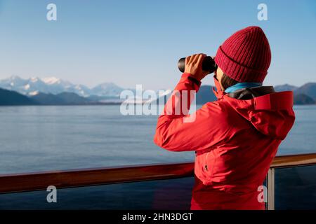 Navire de croisière Alaska Glacier Bay passager regardant les montagnes de l'Alaska avec des jumelles explorant le parc national de Glacier Bay, États-Unis. Femme en voyage à l'intérieur Banque D'Images