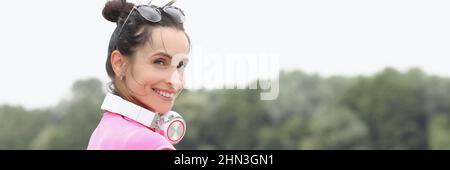Jeune femme souriante avec un casque sur le cou, debout sur le pont Banque D'Images