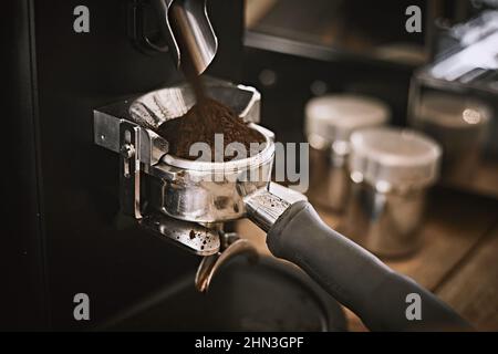 Moulin à café moulant des grains fraîchement torréfiés en poudre. Banque D'Images