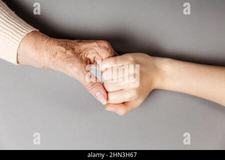 Gros plan sur les mains de la femme âgée et jeune. Pose à plat. Le concept de la Journée internationale des personnes âgées Banque D'Images