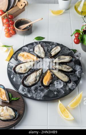 attention sélective. moules crues dans l'évier, étalées sur glace sur une assiette. une spécialité chère. service de restaurant Banque D'Images