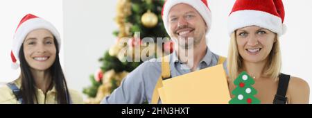 Groupe de posters en chapeaux de père noël rouges tenant des lettres et des boîtes avec des cadeaux Banque D'Images