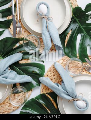 Table de Pâques tropicale. Vue de dessus de table pour Pâques chrétienne avec des œufs de lapin décorés de feuilles de monstère. Tables de Pâques esthétiques. Dîner de Pâques avec lapin, feuilles tropicales et œufs Banque D'Images