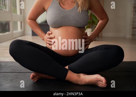 Femme caucasienne mère enceinte assise sur un tapis de yoga tenant le ventre enceinte Banque D'Images