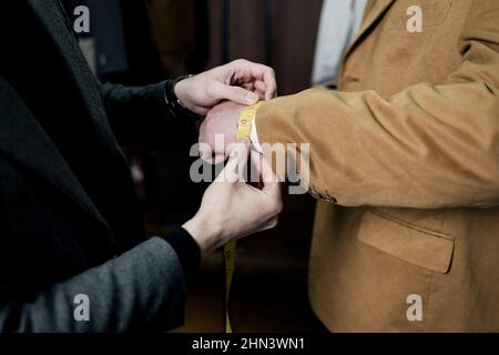 cet ancien modèle s'adapte aux mesures du poignet effectuées par le client dans un atelier d'atelier pour créer un costume classique personnalisé Banque D'Images