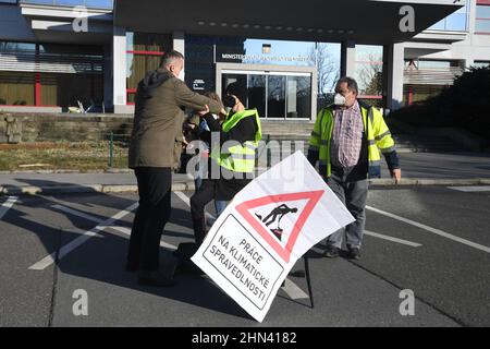 Prague, République tchèque. 14th févr. 2022. Un groupe de militants écologistes a arrêté le flux d'eau vers le bâtiment du ministère de l'Environnement pour protester contre l'accord entre la République tchèque et la Pologne sur l'exploitation minière dans la mine de charbon brun de Turow, le 14 février 2022, à Prague (République tchèque). Il y a un activiste avec la bannière "Work in Climate Justice", qui s'assoit sur une chaise au-dessus de la vanne de la pipe à eau, qu'il avait manipulée auparavant. Un membre du garde de sécurité du ministère, parti, enlève un activiste. Crédit : Katerina Sulova/CTK photo/Alamy Live News Banque D'Images