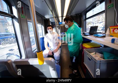 Munich, Allemagne. 14th févr. 2022. Un médecin (r) vaccine un employé de MKT Krankentransport OHG dans le tramway de vaccination de Wettersteinplatz. Le tramway est garé à un autre endroit de la ville tous les jours. Les personnes qui veulent être vaccinées peuvent le faire de 10 h 30 à 5 h 30 chaque jour. Credit: Sven Hoppe/dpa/Alay Live News Banque D'Images