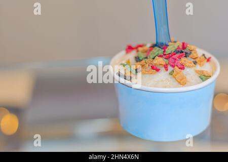 La crème glacée napolitaine se ramasse dans une tasse bleue sur une table en verre Banque D'Images