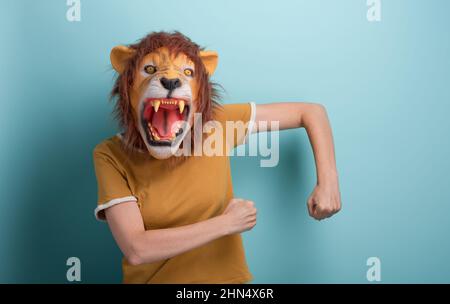 Une jeune femme en masque de lion effectue des mouvements de danse insouciants et gais, isolés sur fond bleu. Banque D'Images