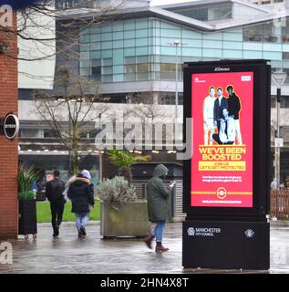 Les gens marchent devant un NHS et HM Government « nous avons été boostés » signe électronique pour annoncer le vaccin de rappel pour combattre Covid-19 à Manchester, Grand Manchester, Angleterre, Royaume-Uni. Le nombre d'infections à Covid-19, à coronavirus ou à Corona continue de diminuer dans le Grand Manchester. 12 364 personnes se sont testées positives dans la région au cours de la semaine se terminant le 8th février 2022, soit une baisse de 35 % par rapport à la semaine précédente. Banque D'Images