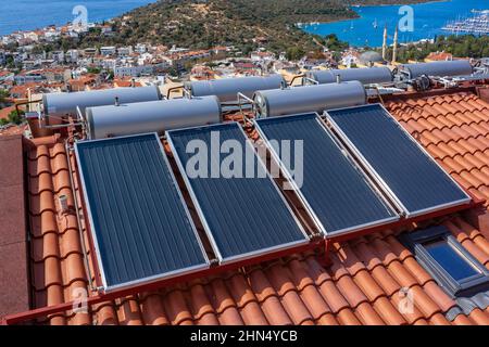 Chauffe-eau solaire installé sur le toit en tuiles de la maison pour le chauffage écologique de l'eau. Grands réservoirs d'eau. Banque D'Images