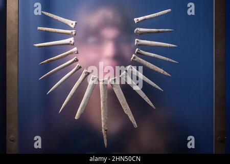 Londres, Royaume-Uni. 14 février 2022. Un membre du personnel pose avec un collier en os d'animaux, Salisbury Plain, Wiltshire, 2100-1800 av. J.-C. Avant-première de « l’univers de Stonehenge » au British Museum », la toute première exposition majeure du Royaume-Uni sur Stonehenge, qui présente plus de 430 000 objets en provenance de Grande-Bretagne, d’Irlande et d’Europe. Les travaux sont exposés du 17 février au 17 juillet 2022. Credit: Stephen Chung / Alamy Live News Banque D'Images