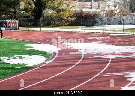 Une piste d'école secondaire a encore de la neige et de la glace au premier tour, car le reste de la neige a fondu. Banque D'Images