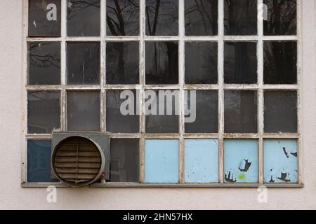 Fenêtre ancienne et cassée de l'usine industrielle avec ventilateur intégré Banque D'Images