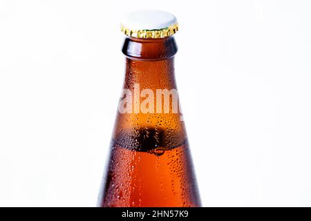 Gros plan sur le col d'une bouteille de verre humide de bière foncée avec un liège sur fond blanc. Boissons alcoolisées. Banque D'Images