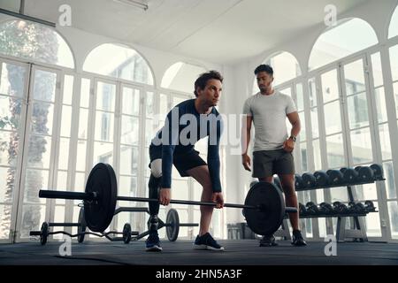 Haltérophilie d'athlète handicapé avec son entraîneur dans la salle de gym moderne. Homme avec une jambe prothétique étant entraîné par son entraîneur Banque D'Images