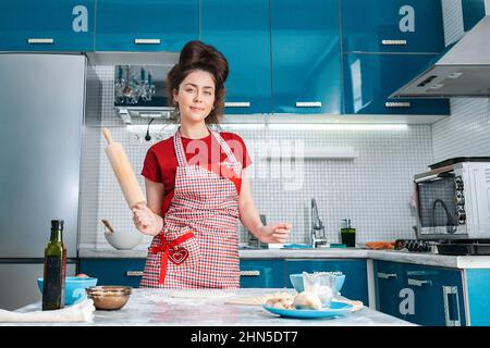 Une jeune femme au foyer pose avec un rouleau dans sa main, dans sa cuisine. Banque D'Images