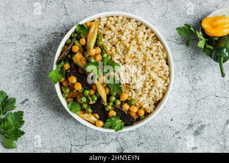 Aubergine pois chiches végétarien curry végétalien avec bulgur dans une casserole sur fond gris, vue du dessus. Cuisine indienne. Nourriture saine. Base végétale. Banque D'Images