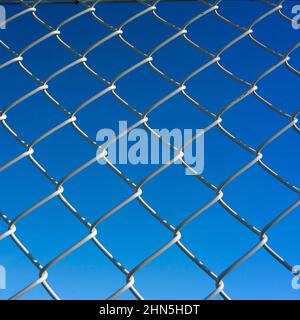 Vue rapprochée d'une clôture à maillons de chaîne contre un ciel bleu clair Banque D'Images