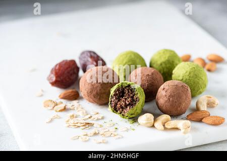 Boules d'énergie saine avec des dattes et des noix enrobées de poudre de matcha de thé vert. Truffes végétaliennes sans sucre Banque D'Images