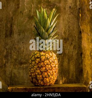 Ananas reposant sur une surface en bois sur un fond rustique Banque D'Images