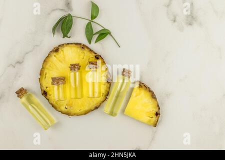 cosmétiques vivants à base d'ananas. agent hydratant et azurant en bouteilles de verre avec bouchon sur une tranche d'ananas frais. vue du dessus Banque D'Images