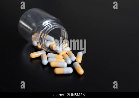 Pilules sur une table en bois sombre, médicaments en capsules dispersées d'une bouteille. Contexte pour la pharmacie, les antibiotiques, les vitamines Banque D'Images