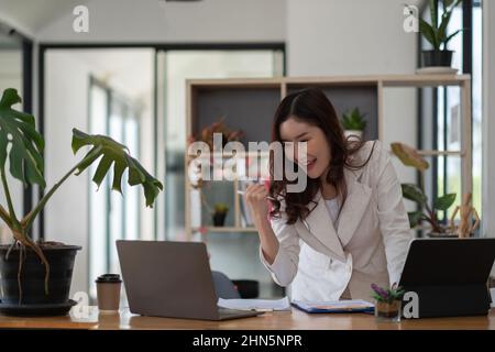 Entrepreneur de belle entreprise asiatique jeune femme travaillant avec un ordinateur portable et célébrant à la maison avec son succès de travail gai et bonheur, petit Banque D'Images