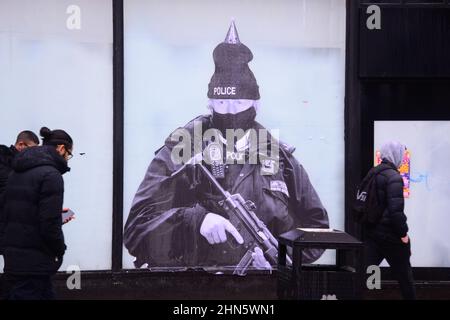 Manchester, Royaume-Uni, 14th février 2022. Une fresque humoristique présentant le Premier ministre britannique Boris Johnson est apparue sur l'ancien magasin Debenhams dans le centre de Manchester, au Royaume-Uni. Réalisée par 'Foka Wolf', une artiste de rue, la fresque a la tête de Boris Johnson, portant un chapeau de fête, sur l'image d'un policier armé. Il y a une enquête de la police métropolitaine en cours sur des rassemblements sociaux ou des parties au 10 Downing Street pendant les écluses de Covid-19, de coronavirus ou de Corona. Un rapport de la fonctionnaire Sue Gray critiquait certains rassemblements dans ce pays. Crédit : Terry Waller/Alay Live News Banque D'Images