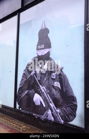 Manchester, Royaume-Uni, 14th février 2022. Une fresque humoristique présentant le Premier ministre britannique Boris Johnson est apparue sur l'ancien magasin Debenhams dans le centre de Manchester, au Royaume-Uni. Réalisée par 'Foka Wolf', une artiste de rue, la fresque a la tête de Boris Johnson, portant un chapeau de fête, sur l'image d'un policier armé. Il y a une enquête de la police métropolitaine en cours sur des rassemblements sociaux ou des parties au 10 Downing Street pendant les écluses de Covid-19, de coronavirus ou de Corona. Un rapport de la fonctionnaire Sue Gray critiquait certains rassemblements dans ce pays. Crédit : Terry Waller/Alay Live News Banque D'Images