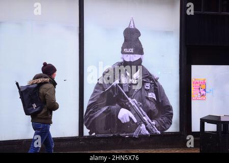 Manchester, Royaume-Uni, 14th février 2022. Une fresque humoristique présentant le Premier ministre britannique Boris Johnson est apparue sur l'ancien magasin Debenhams dans le centre de Manchester, au Royaume-Uni. Réalisée par 'Foka Wolf', une artiste de rue, la fresque a la tête de Boris Johnson, portant un chapeau de fête, sur l'image d'un policier armé. Il y a une enquête de la police métropolitaine en cours sur des rassemblements sociaux ou des parties au 10 Downing Street pendant les écluses de Covid-19, de coronavirus ou de Corona. Un rapport de la fonctionnaire Sue Gray critiquait certains rassemblements dans ce pays. Crédit : Terry Waller/Alay Live News Banque D'Images