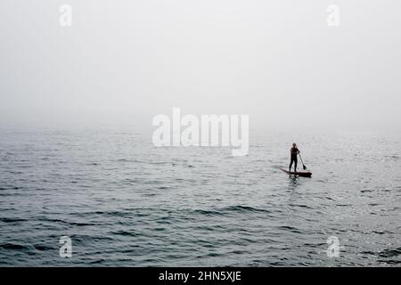 Sup, paddleboard en stand-up, homme solitaire flottant dans le brouillard Banque D'Images